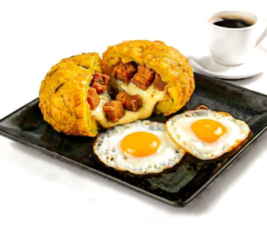Delicious Ecuadorian breakfast featuring mote pillo, fried eggs, and coffee on a black plate.