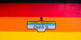 Vibrant Church Street sign in Toronto's Church-Wellesley Village with rainbow colors.