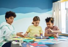 Los Mejores Programas Extraescolares en Hoboken para 2026: Guía Completa para Padres Children focusing on an art project with colored papers in a playful art class setting.