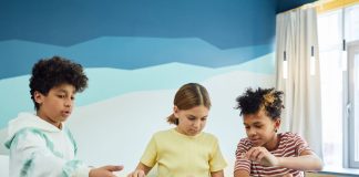 Children focusing on an art project with colored papers in a playful art class setting.