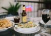 An inviting dining setup featuring tacos, chips, beer, and wine on a glass table in a relaxed indoor setting.