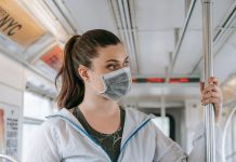 An adult woman wearing a face mask rides public transportation, focusing on safety and protection.