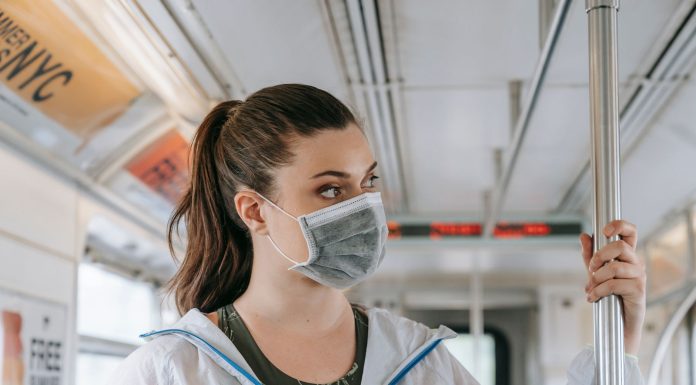 An adult woman wearing a face mask rides public transportation, focusing on safety and protection.