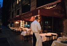 Elegant outdoor dining area at night with waitstaff preparing tables.