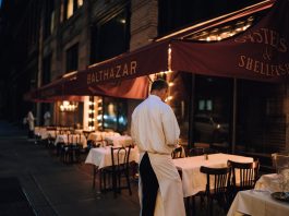 Elegant outdoor dining area at night with waitstaff preparing tables.