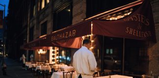 Elegant outdoor dining area at night with waitstaff preparing tables.