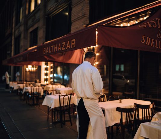 Elegant outdoor dining area at night with waitstaff preparing tables.