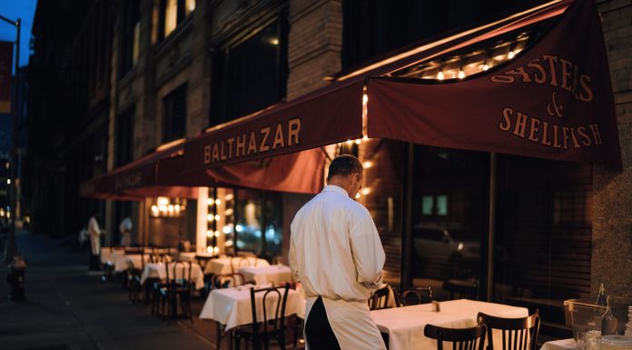 Elegant outdoor dining area at night with waitstaff preparing tables.
