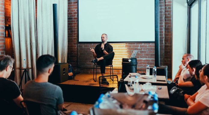 Stevens and Harvard Bring Educators’ Conference to Jersey City A business seminar with a speaker addressing an attentive audience in a modern conference setting.