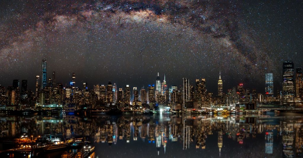 Nighttime view of New York City with stars reflecting on the water.