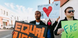 A diverse group of protesters holding signs advocating for equal rights and world peace.