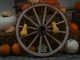 Rustic autumn display featuring pumpkins and a wooden wagon wheel on hay bales, perfect for fall decor inspiration.